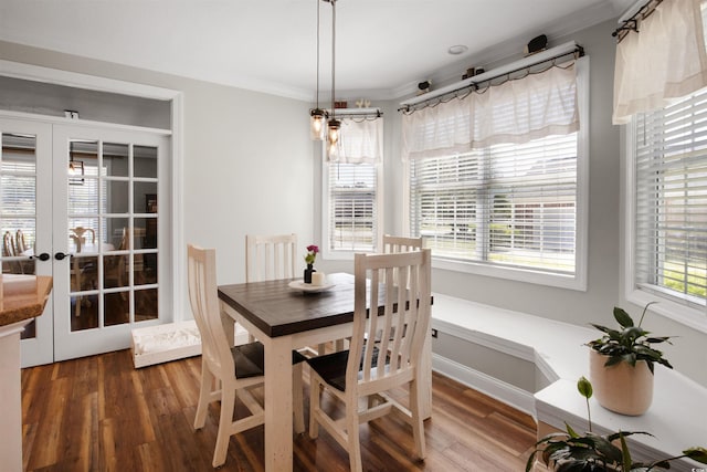 dining space with a chandelier, french doors, crown molding, and dark wood-type flooring