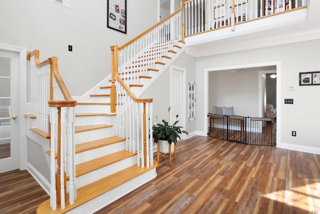 staircase with ornamental molding, a high ceiling, and hardwood / wood-style flooring