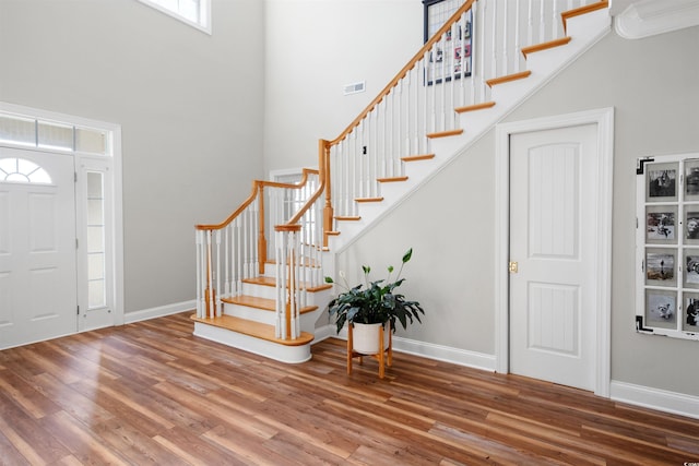 entrance foyer with wood-type flooring and a towering ceiling