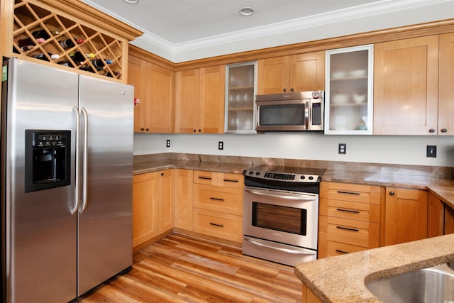 kitchen featuring light stone countertops, stainless steel appliances, crown molding, and light hardwood / wood-style floors