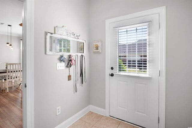 entryway featuring light tile patterned flooring and ornamental molding