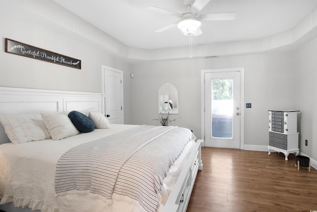 bedroom featuring a raised ceiling, ceiling fan, and dark wood-type flooring