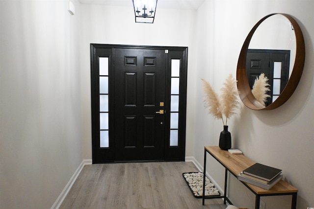 foyer entrance with light hardwood / wood-style floors and a chandelier