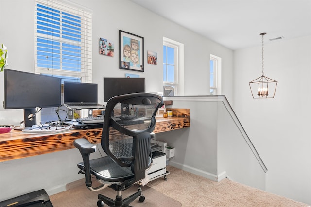 carpeted home office with a chandelier