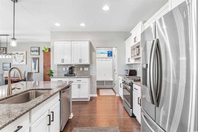 kitchen with light stone countertops, white cabinetry, sink, hanging light fixtures, and stainless steel appliances