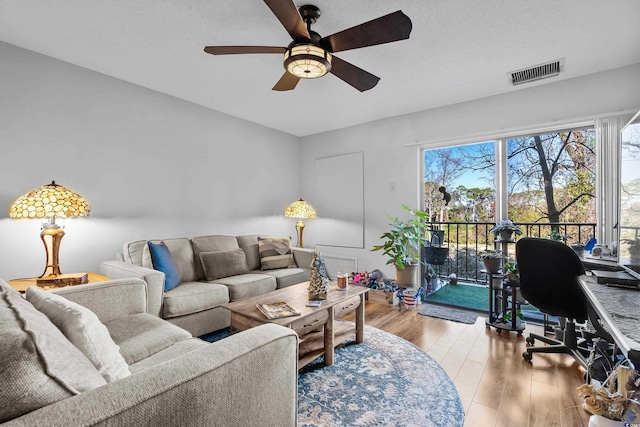 living room with a healthy amount of sunlight, a textured ceiling, ceiling fan, and light hardwood / wood-style flooring