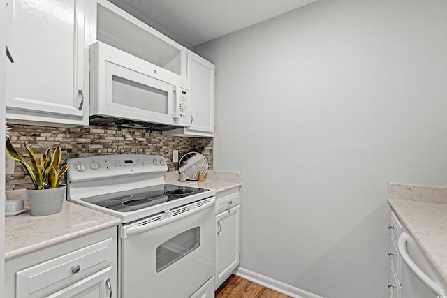 kitchen with tasteful backsplash, white appliances, light hardwood / wood-style flooring, and white cabinets