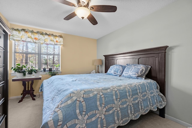 bedroom with ceiling fan, light carpet, and a textured ceiling