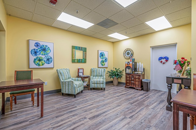 sitting room with hardwood / wood-style flooring and a drop ceiling