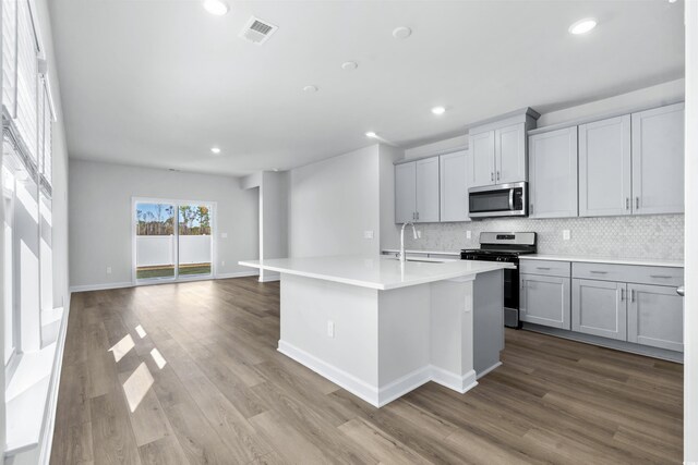 2039 Copper Creek Loop, Longs, SC 29568 - kitchen featuring appliances with stainless steel finishes, sink, light wood-type flooring, tasteful backsplash, and a kitchen island with sink