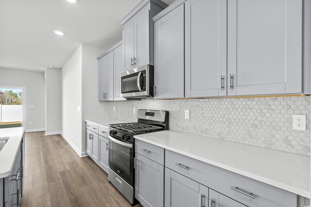 2039 Copper Creek Loop, Longs, SC 29568 - kitchen with gray cabinets, light hardwood / wood-style floors, tasteful backsplash, and stainless steel appliances