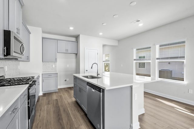 2039 Copper Creek Loop, Longs, SC 29568 - kitchen featuring appliances with stainless steel finishes, a kitchen island with sink, gray cabinetry, sink, and light hardwood / wood-style flooring