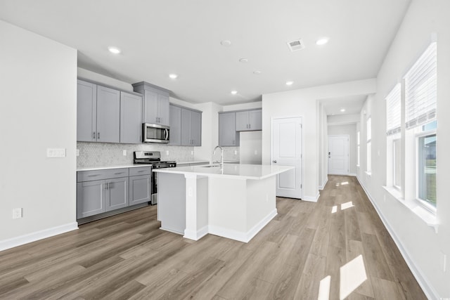 2039 Copper Creek Loop, Longs, SC 29568 - kitchen with a kitchen island with sink, light hardwood / wood-style flooring, backsplash, stainless steel appliances, and gray cabinets