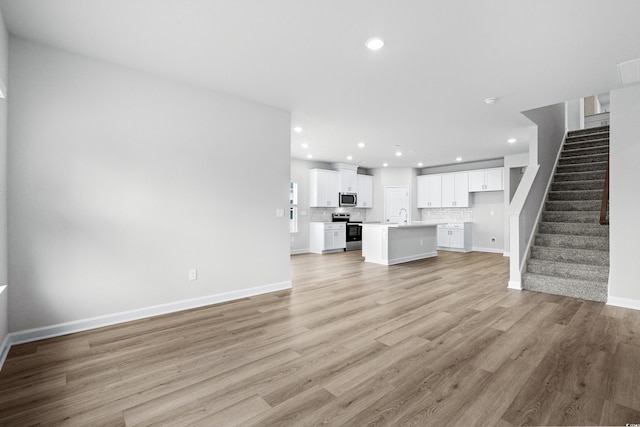 unfurnished living room featuring sink and light wood-type flooring