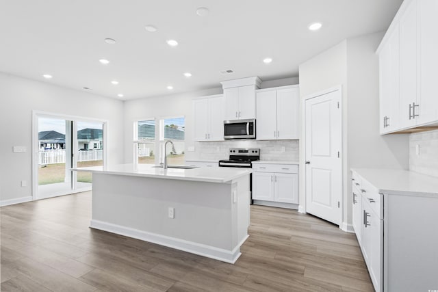 kitchen with white cabinetry, stainless steel appliances, a kitchen island with sink, and sink