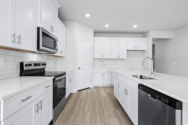 kitchen featuring white cabinetry, stainless steel appliances, sink, and light stone counters