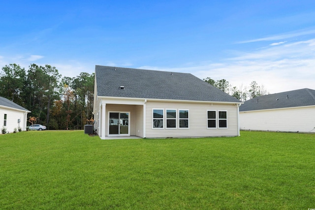 rear view of property with central AC unit and a lawn