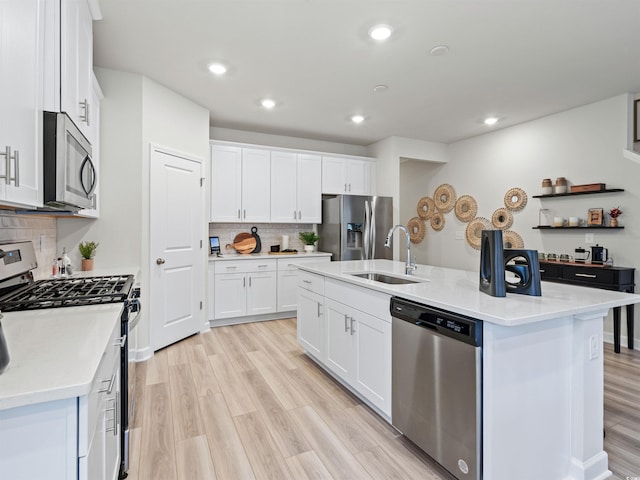 kitchen featuring sink, white cabinetry, tasteful backsplash, appliances with stainless steel finishes, and an island with sink