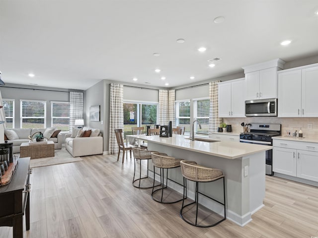 kitchen featuring white cabinetry, an island with sink, appliances with stainless steel finishes, and sink