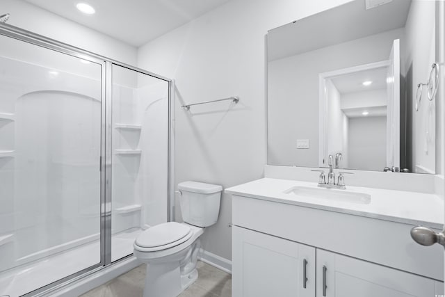 bathroom featuring vanity, a shower with shower door, and toilet