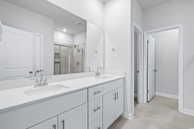 bathroom with a shower with door, vanity, and tile patterned floors