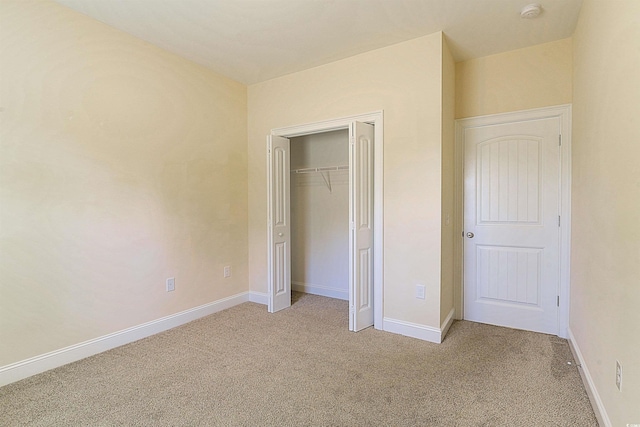 unfurnished bedroom with light carpet and a closet