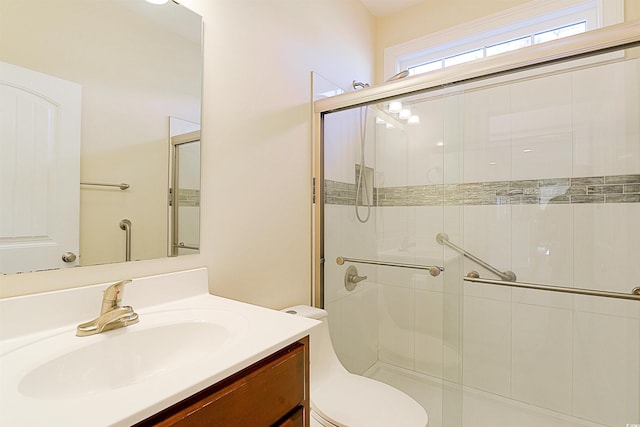 bathroom featuring vanity, toilet, and a shower with door