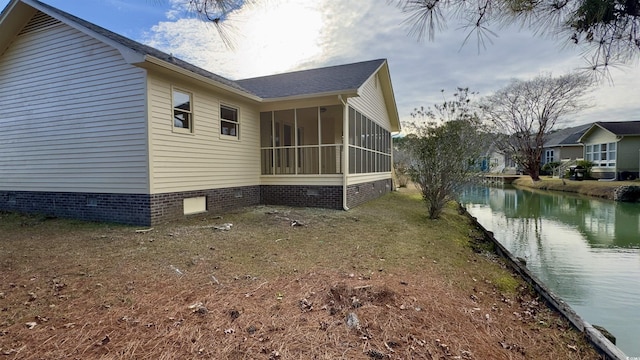 view of side of home featuring a water view and a sunroom