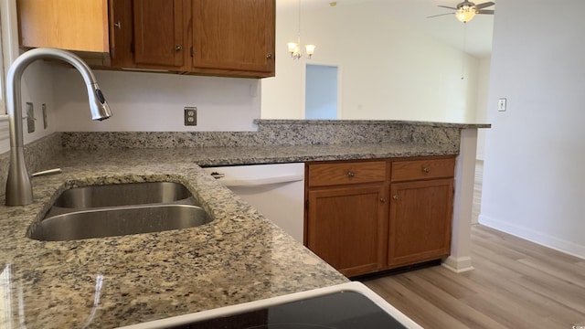 kitchen featuring sink, dishwasher, light stone countertops, light hardwood / wood-style floors, and kitchen peninsula