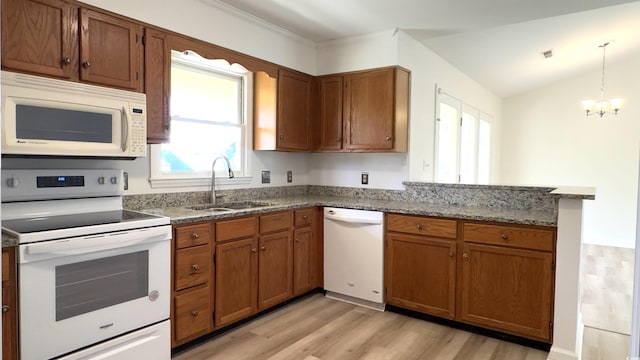 kitchen featuring sink, white appliances, light hardwood / wood-style floors, decorative light fixtures, and kitchen peninsula