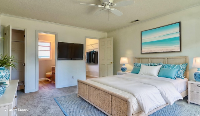 carpeted bedroom with ornamental molding, a walk in closet, ceiling fan, a textured ceiling, and a closet