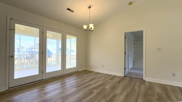 spare room with vaulted ceiling, wood-type flooring, and a notable chandelier