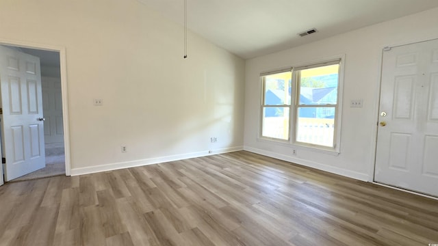 spare room with vaulted ceiling and light wood-type flooring