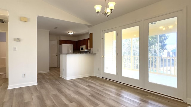 kitchen with vaulted ceiling, light wood-type flooring, white appliances, light stone counters, and an inviting chandelier