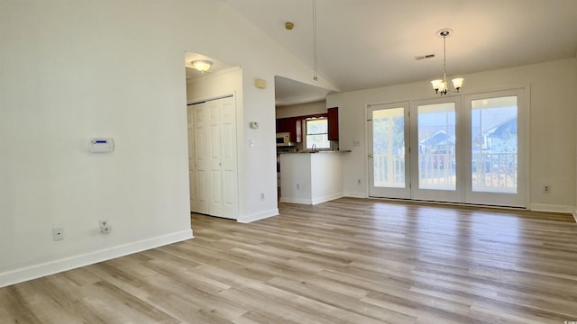 unfurnished living room featuring an inviting chandelier, high vaulted ceiling, and light hardwood / wood-style floors