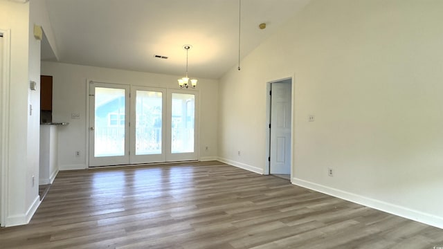 spare room with a notable chandelier, light hardwood / wood-style flooring, and high vaulted ceiling