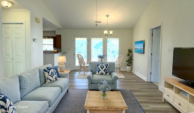 living room with a healthy amount of sunlight, lofted ceiling, dark hardwood / wood-style flooring, and a notable chandelier