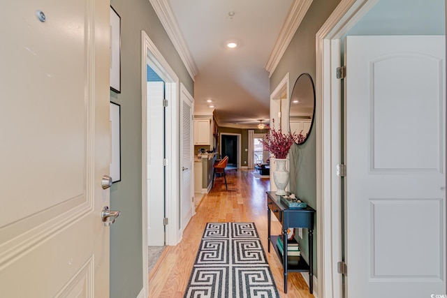 hallway with ornamental molding and light hardwood / wood-style flooring