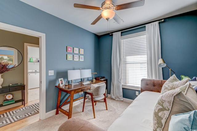 office space with washer / clothes dryer, ceiling fan, and light colored carpet