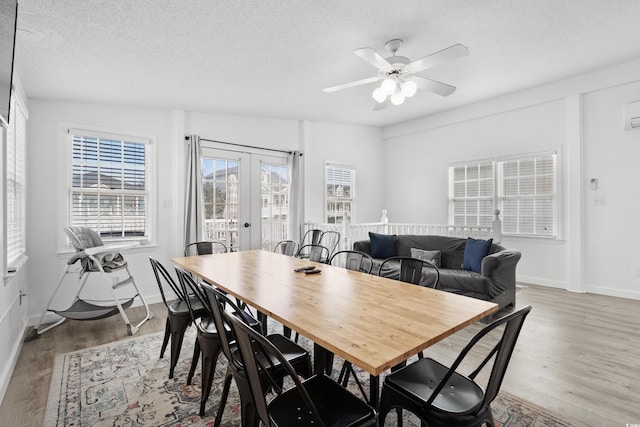 dining room with ceiling fan, french doors, light hardwood / wood-style floors, and a textured ceiling