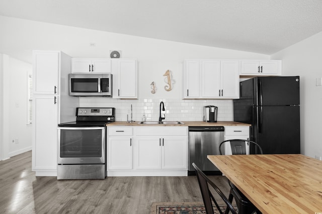 kitchen featuring lofted ceiling, backsplash, white cabinets, sink, and stainless steel appliances