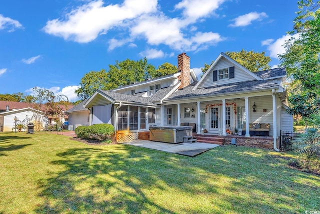 back of property featuring a lawn, a sunroom, ceiling fan, a hot tub, and a patio area