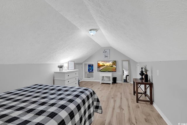 bedroom with lofted ceiling, light wood-type flooring, and a textured ceiling