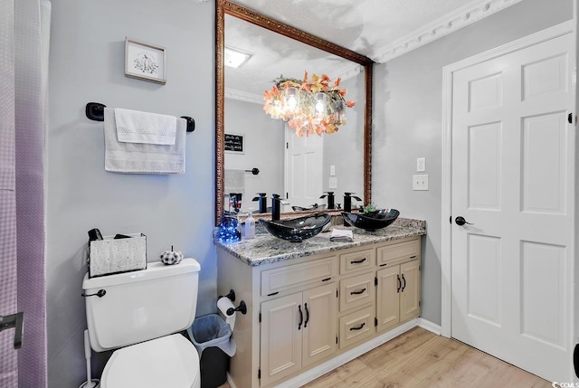 bathroom featuring vanity, a textured ceiling, crown molding, wood-type flooring, and toilet