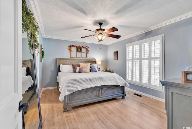 bedroom featuring a textured ceiling, light hardwood / wood-style floors, ceiling fan, and crown molding