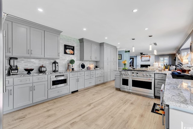 kitchen with range with two ovens, light hardwood / wood-style flooring, ceiling fan, gray cabinets, and decorative backsplash