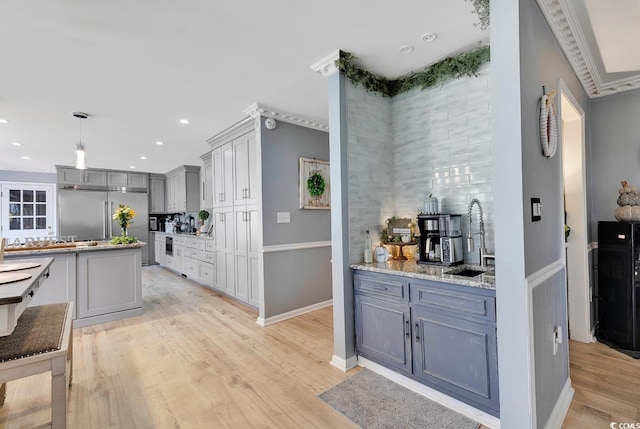 kitchen with gray cabinets, stainless steel built in fridge, light hardwood / wood-style floors, and decorative light fixtures