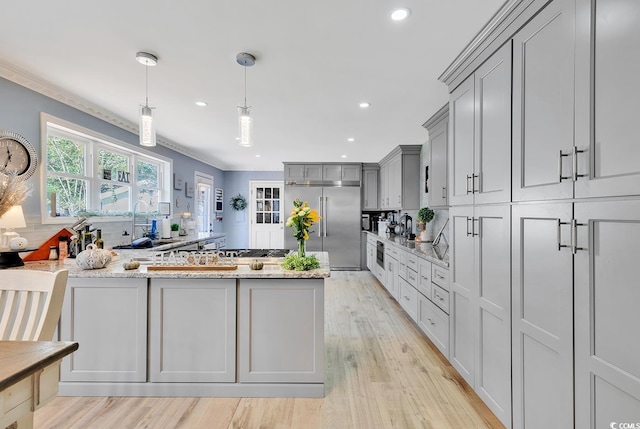 kitchen with light stone countertops, sink, hanging light fixtures, gray cabinets, and stainless steel built in fridge