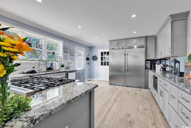 kitchen with gray cabinets, light stone counters, and stainless steel appliances