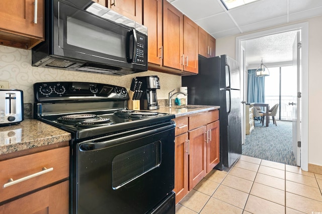 kitchen with light stone countertops, black range with electric stovetop, sink, and light tile patterned floors